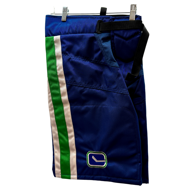 Warrior NHL Pro Return Vancouver Canucks Pant Shells folded in half showing Vancouver Canucks 'stick in the rink' logo, hanging from clothes  hanger